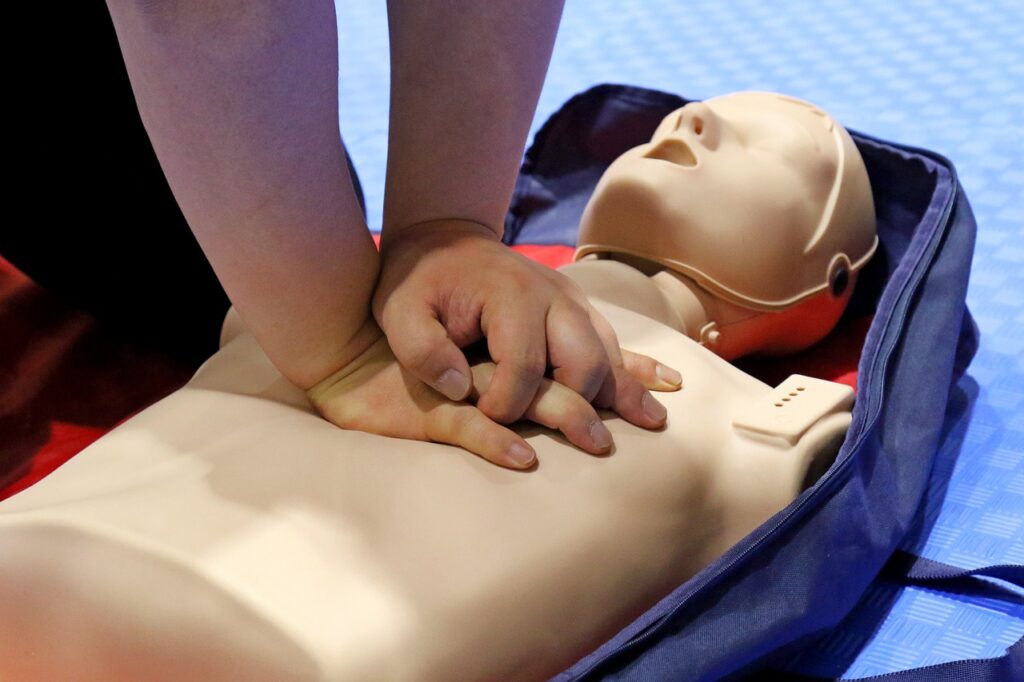 CPR manikin with someone practicing CPR.